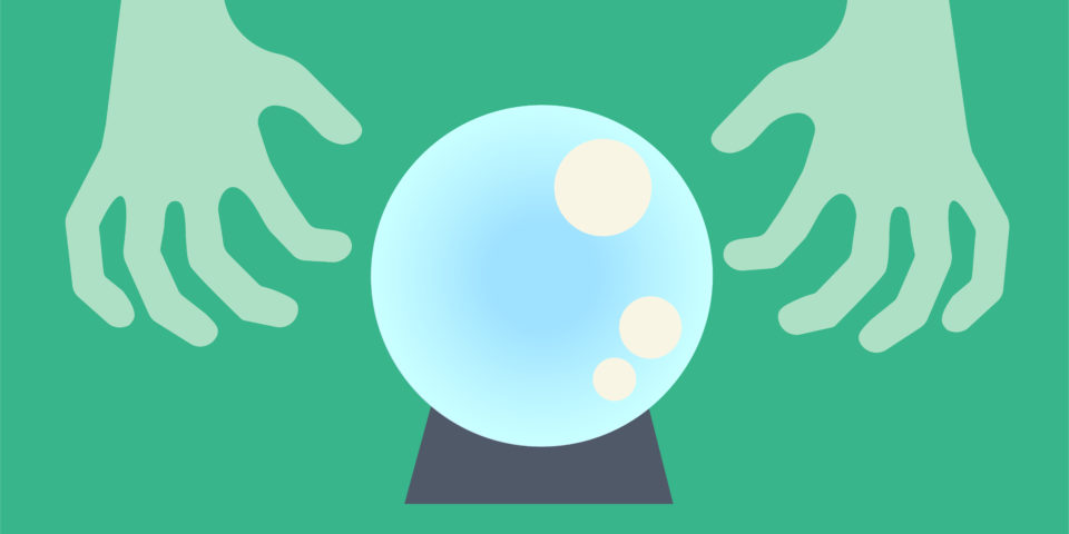Hands hover over a crystal ball, being used to tell the future